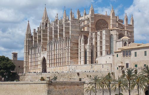 ein großes Steingebäude mit Türmen und der Kathedrale von Palma im Hintergrund