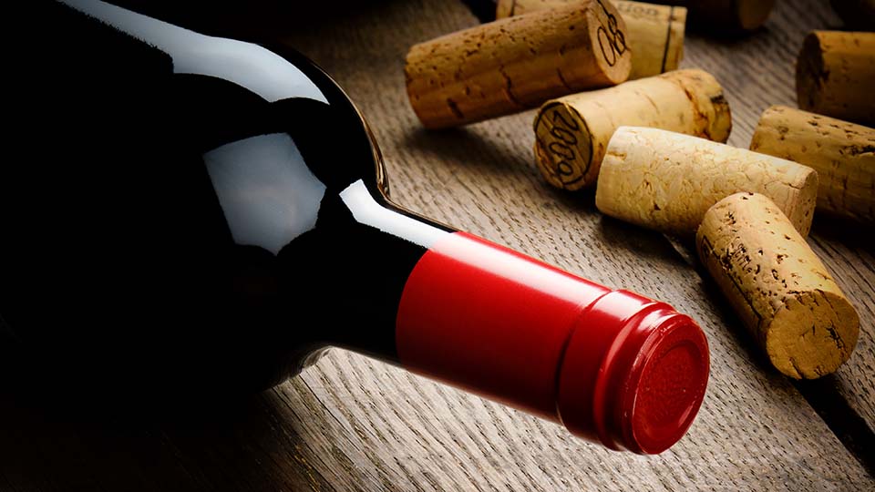 una botella de vino junto a un racimo de plátanos